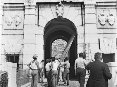 1961. Operai che smontano l’enorme portone in legno di accesso al Castello per consentire il delicatissimo passaggio della Locomotiva.